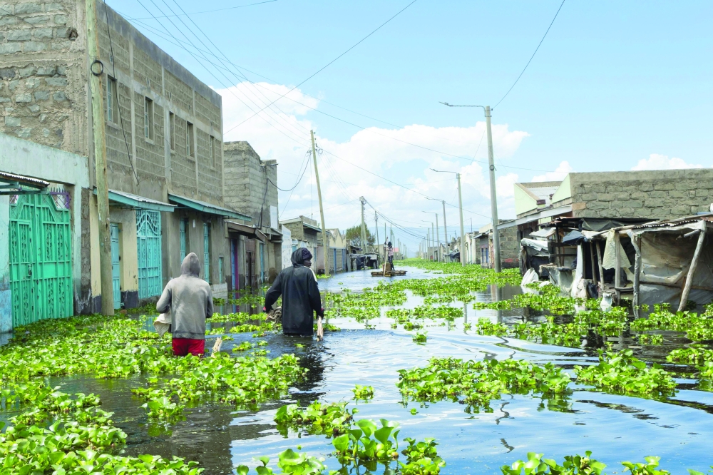 Residents wade through flood water carrying long poles as they make for suitable fishing grounds at what used to be their homes at Kihoto estate in Naivasha on November 17, 2025.  Heavy rains in Kenya have caused the waters of Lake Naivasha, a hundred kilometres northwest of capital Nairobi, to flood nearby homes, displacing families.  (Photo by Tony KARUMBA / AFP)