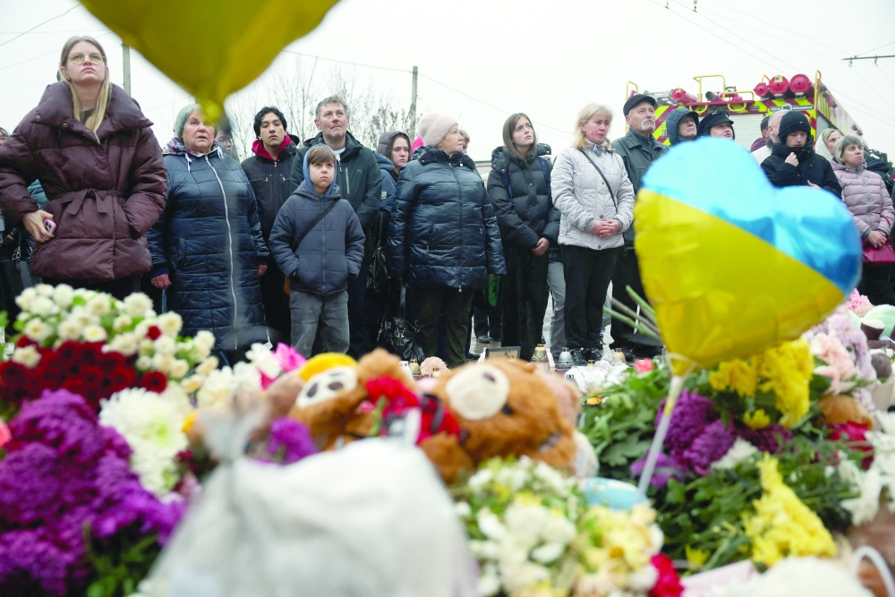 People stand at a makeshift memorial for the victims who were killed when a Russian missile hit an apartment building in Ternopil, Ukraine. — Reuters