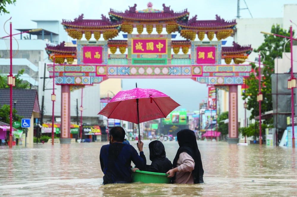 People wade through a flooded area in Hat Yai district, Songkhla, Thailand, November 22, 2025. 