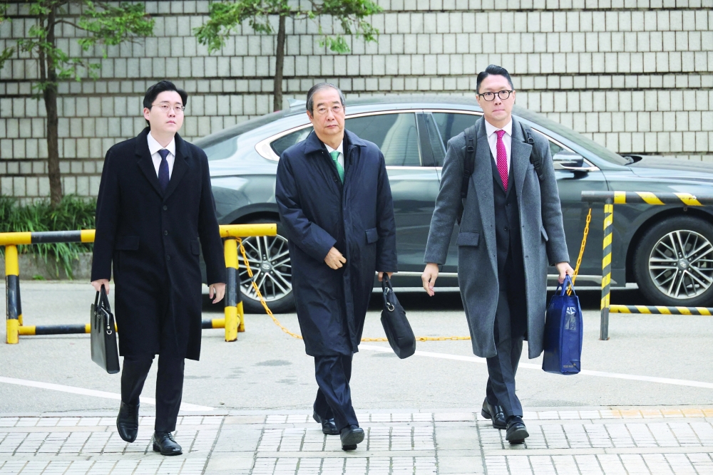 Former PM Han Duck-soo (C) arrives for closing hearing at the Seoul Central District Court. — Reuters 