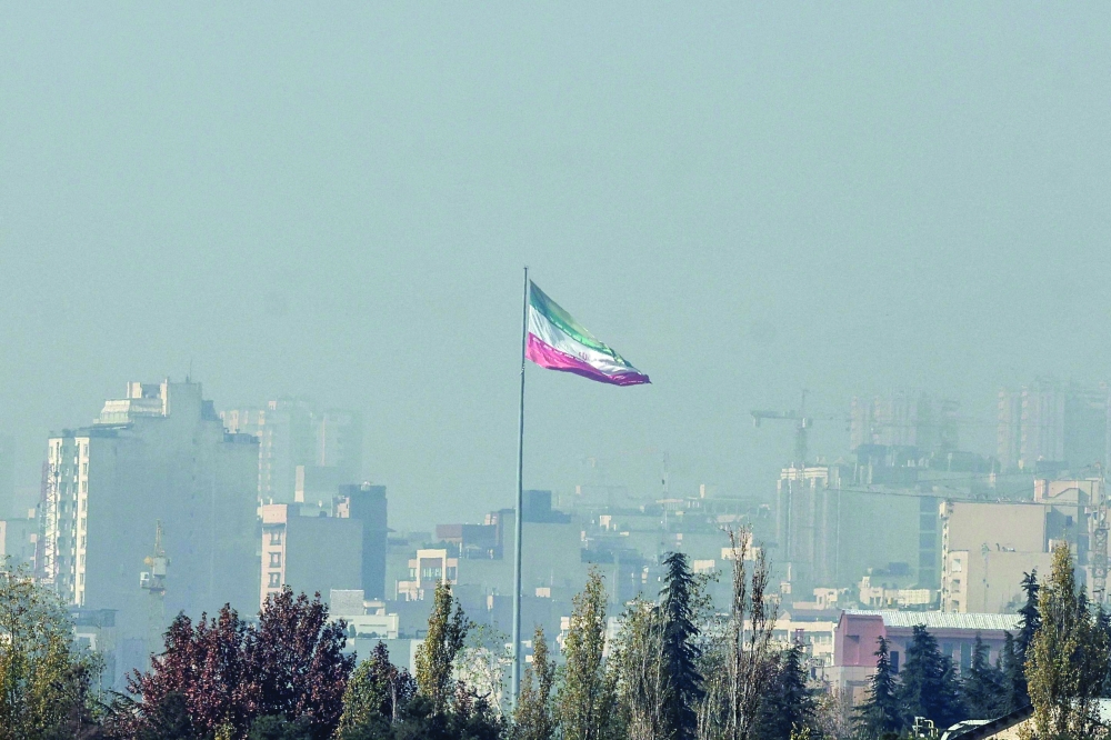 The Iranian flag flutters over the capital blanketed in winter's heavy smog, in Tehran. — AFP