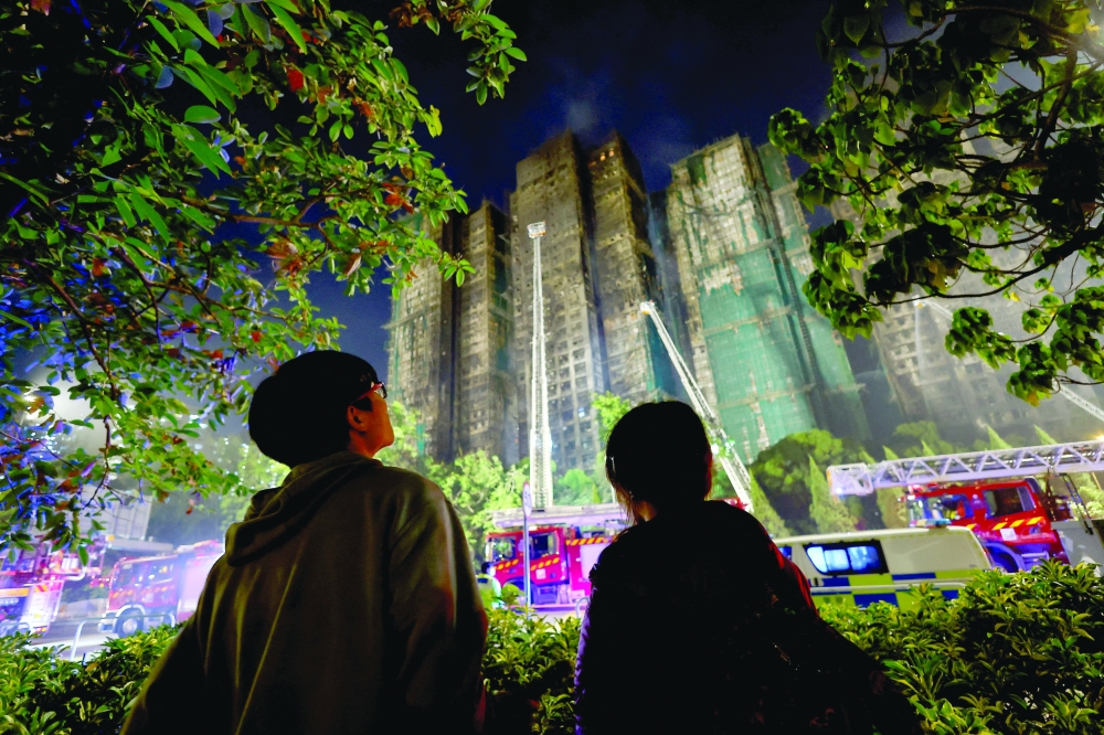 People stand near the scene of a deadly fire, which broke out yesterday at Wang Fuk Court housing complex in Hong Kong. - Reuters