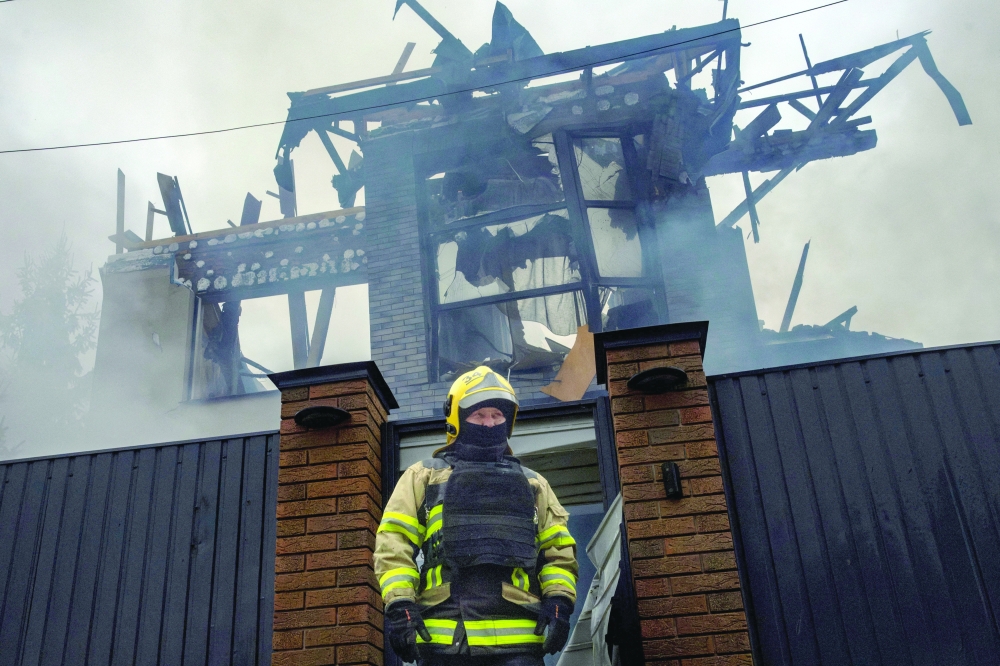 A firefighter steps out of a house that went up in flames after attacks on Kyiv. — Reuters