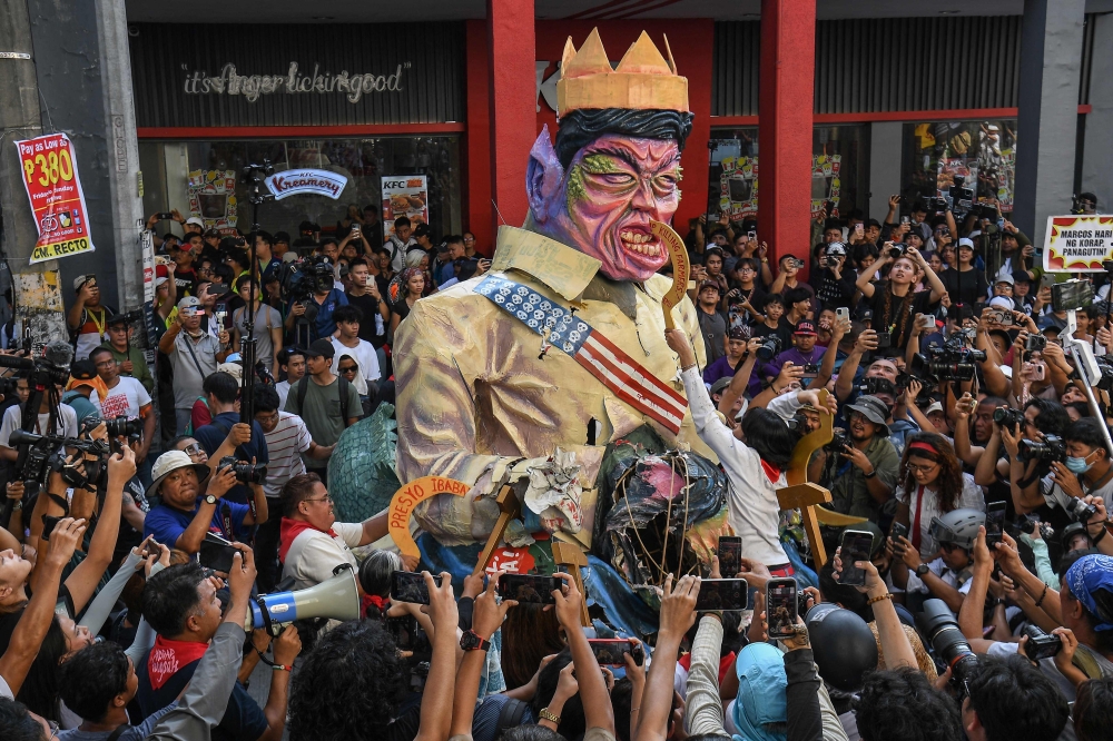 Protesters destroy an effigy of Philippine President Ferdinand Marcos during an anti-corruption rally near Malacanang Palace in Manila on November 30, 2025. 