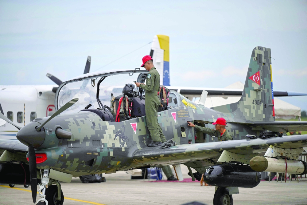 A Venezuelan military member stands on the wing of a T-27 Tucano aircraft. — AFP