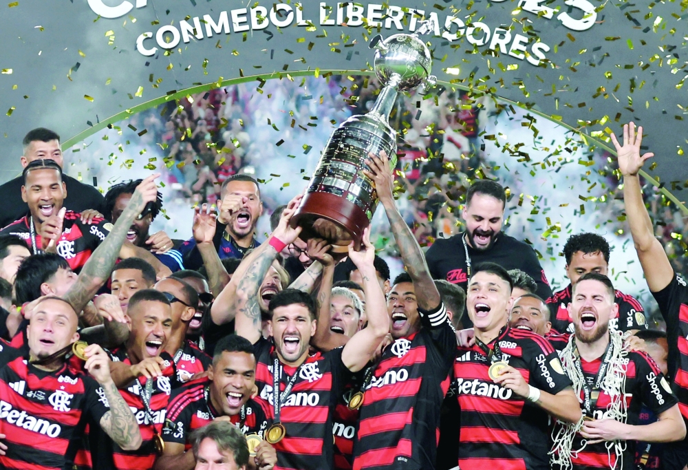 Flamengo's Giorgian de Arrascaeta and Bruno Henrique celebrate with the trophy and team-mates after winning the Copa Libertadores. — Reuters