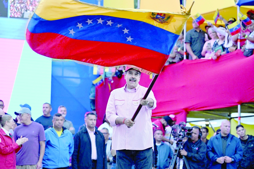 Venezuela's President Nicolas Maduro waves a national flag during a rally in Caracas. — AFP