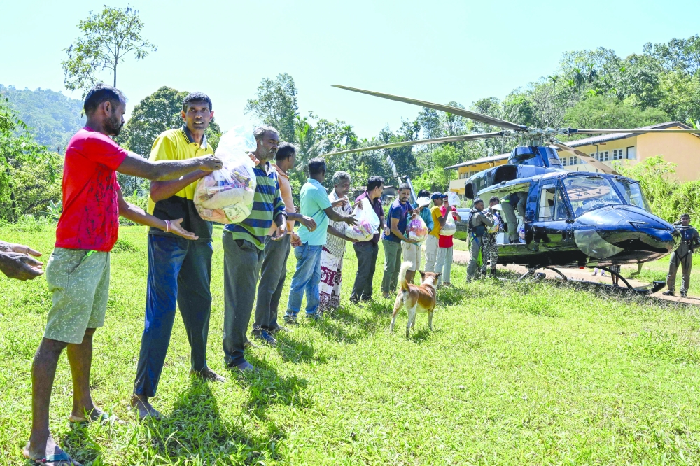 Volunteers help unload dry rations from a helicopter to marooned residents, east of Colombo. — AFP