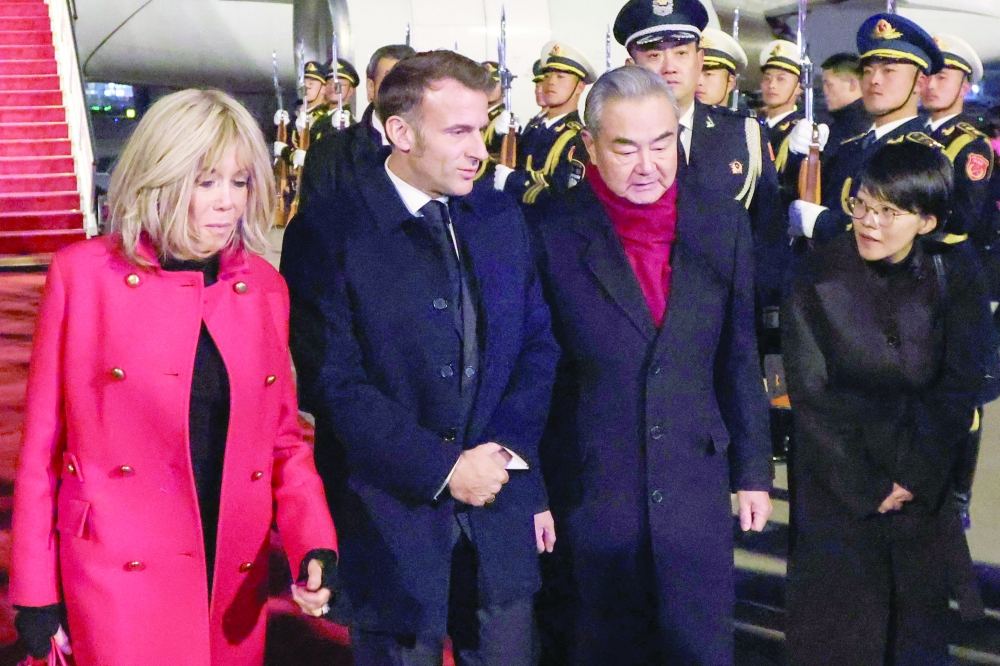 China's FM Wang Yi (2nd R) receives France's President Emmanuel Macron and his wife Brigitte Macron upon their arrival, in Beijing. — AFP