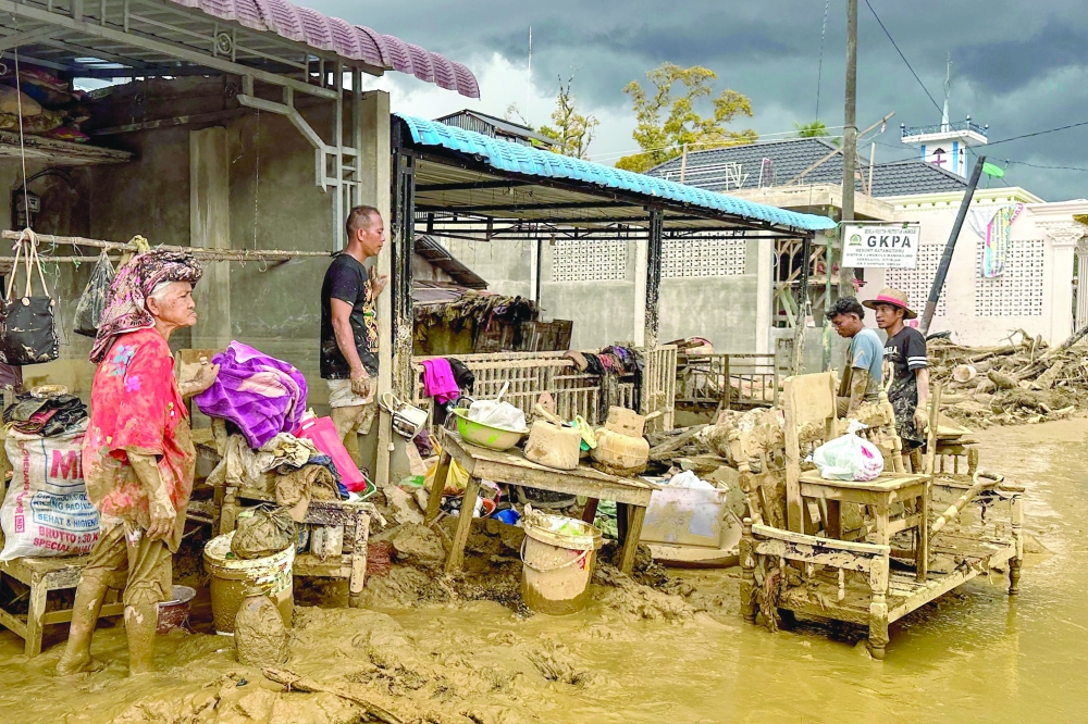 Villagers affected by flash floods clean mud from their home and belongings in Aek Ngadol village, South Tapanuli Regency, North Sumatra province. — AFP