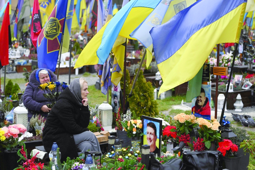 People mourn at the graves of Ukrainian servicemen at the Lychakiv cemetery, in Lviv. — AFP