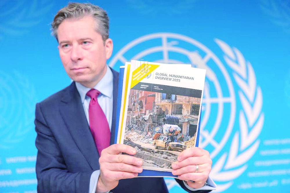 Tom Fletcher holds a copy of the Global Humanitarian overview after a press conference in Geneva. — Reuters 