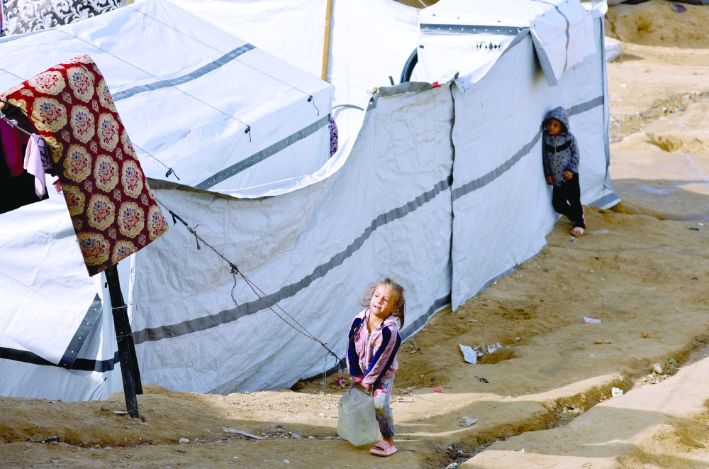A displaced Palestinian child carries a water container as she walks at a tent camp in Deir Al-Balah, in the central Gaza Strip, December 9, 2025. REUTERS/
