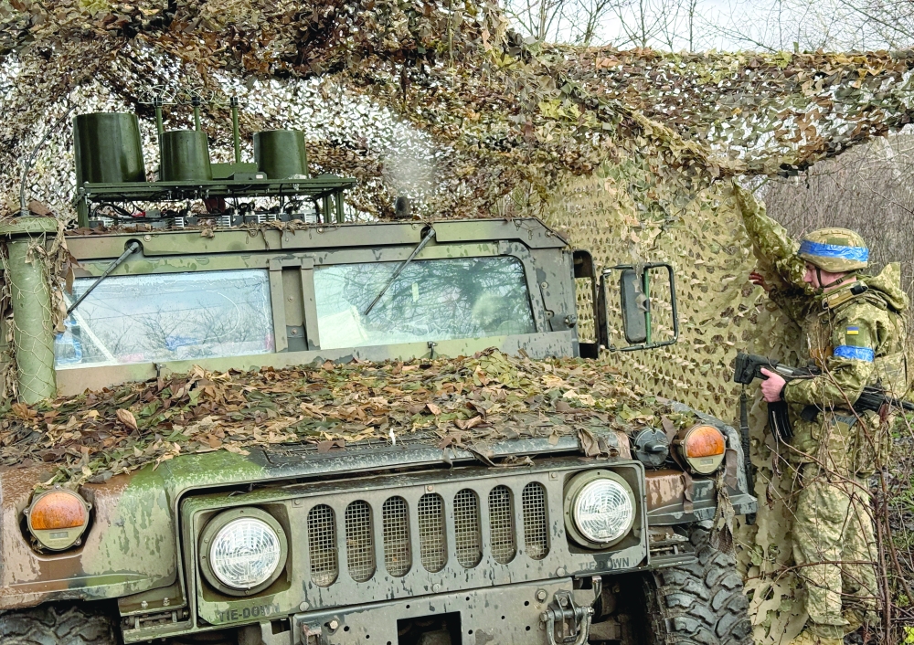 Ukrainian serviceman camouflages a Humvee vehicle near the frontline town of Kupiansk, Ukraine. — Reuters