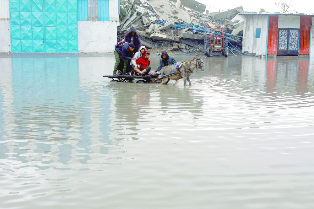 Palestinians ride a donkey-drawn cart on a rain-flooded street in Gaza City on Friday. — Reuters