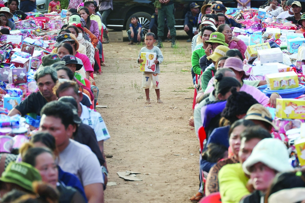 A boy holding a supply stands among people waiting to collect supplies at Batthkav refugee camp, Cambodia. — Reuters 