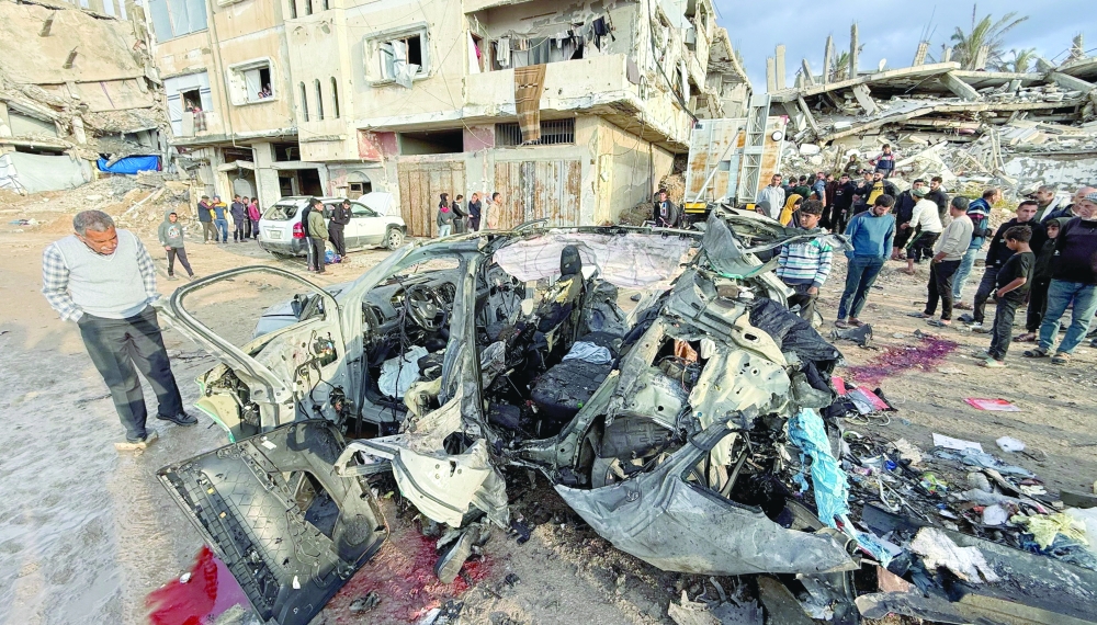 Palestinians inspect the site of an Israeli strike on a car in Gaza City, on Saturday. — Reuters