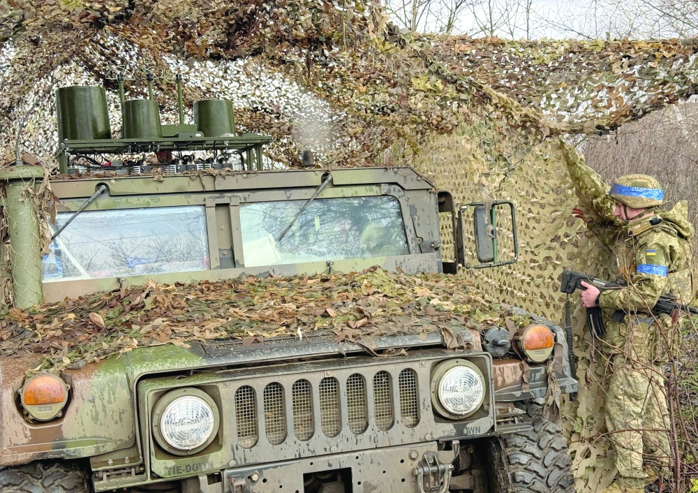 Ukrainian serviceman camouflages a Humvee vehicle, amid Russia's attack on Ukraine, near the frontline town of Kupiansk, Ukraine. - Reuters