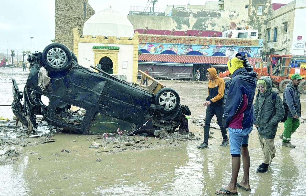 Moroccans looks at a destroyed vehicle and other debris following a flash flood, in the coastal town of Safi, some 300 kilometres (186 miles) south of the capital Rabat on December 15, 2025. A flash flood and a muddy torrent in the Moroccan coastal town killed at least 37, local officials said December 15, as search and rescue operations continued. Drought-hit Morocco often faces severe weather, but the flooding in Safi is already the deadliest such disaster in at least a decade.