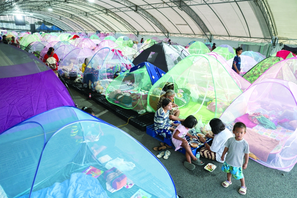 Displaced people eat dinner at a temporary shelter along a disputed border area, in Buriram province. — Reuters