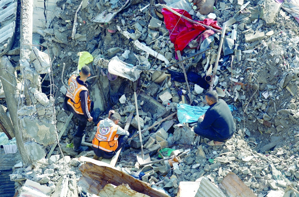 A man watches as members of the Palestinian Civil Defence participate in a search and rescue operation at the site of a house that was partially destroyed during the war and collapsed on Tuesday, at Shati refugee camp in Gaza City. - Reuters