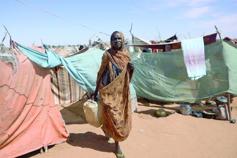 A Sudanese displaced woman carries a water container at a camp, North Darfur. — Reuters