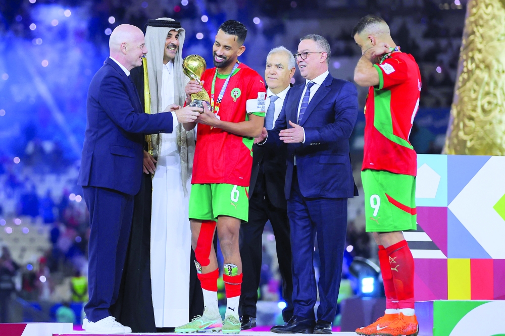 FIFA President Gianni Infantino (L) and Qatar Emir Sheikh Tamim bin Hamad Al-Thani (2nd-L) present the trophy to Morocco's midfielder #6 Mohamed Rabie Hrimat and Morocco's forward #9 Abderrazzaq Hamed Allah after their team's victory in the FIFA Arab Cup 2025 final football match between Jordan and Morocco at the Lusail Stadium  Stadium, in Lusail on December 18, 2025. (Photo by Karim JAAFAR / AFP)
