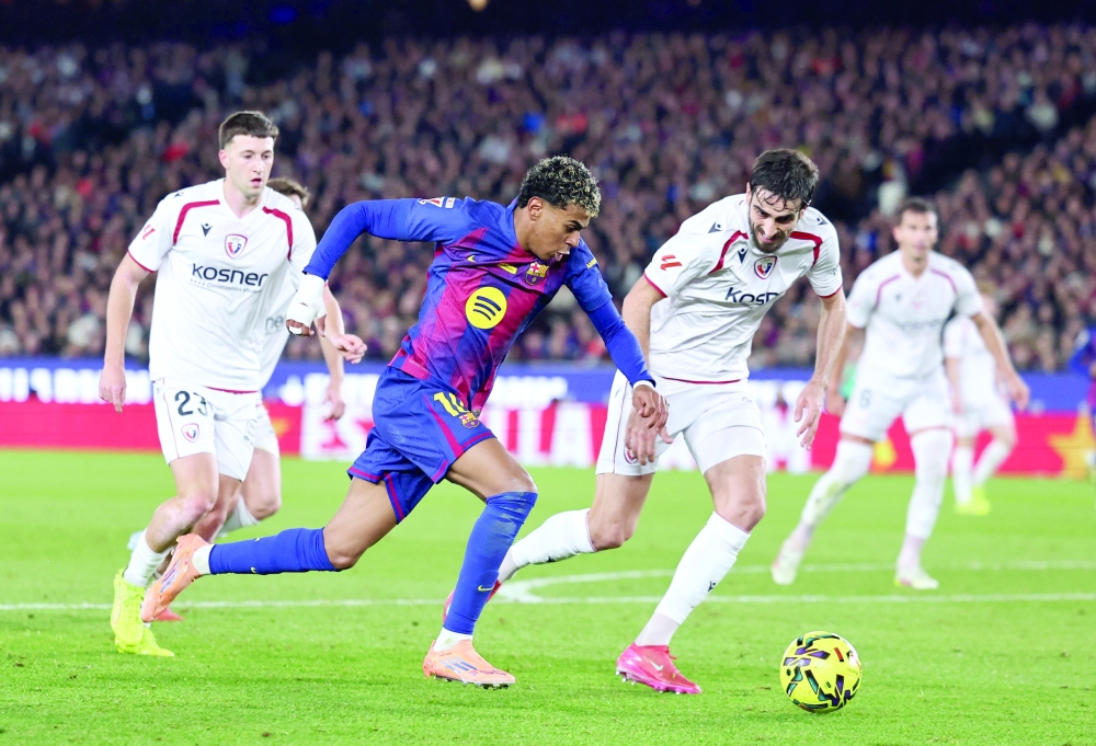 TOPSHOT - Barcelona's Spanish forward #10 Lamine Yamal fights for the ball with Osasuna's Spanish defender #24 Alejandro Catena as he attempts to score during the Spanish league football match between FC Barcelona and CA Osasuna at Camp Nou Stadium in Barcelona on December 13, 2025. (Photo by Josep LAGO / AFP)
