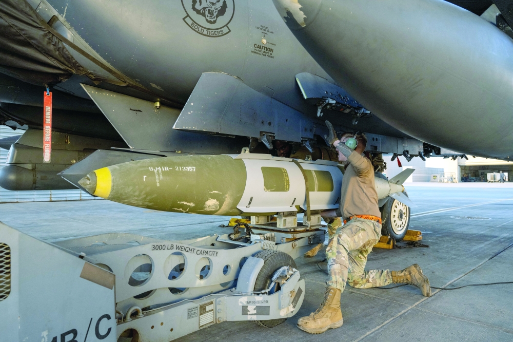 A US Airman attaches a GBU-31 munitions system to an F-15E Strike Eagle in the US Central Command area of responsibility. — AFP