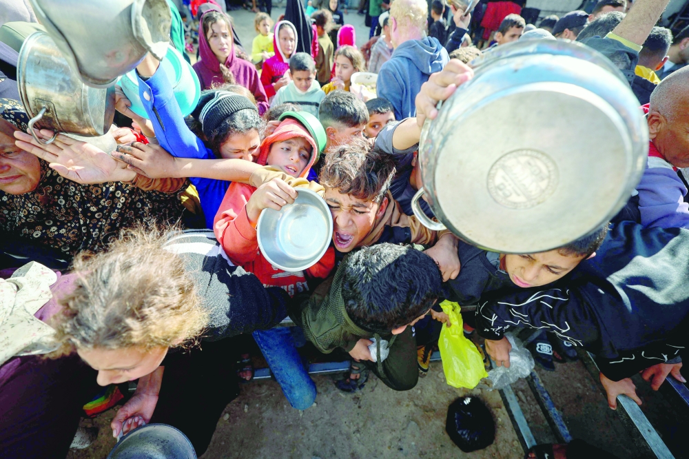 Palestinians gather to receive food portions at a charity kitchen in the Nuseirat refugee camp in the central Gaza Strip on Saturday. — AFP