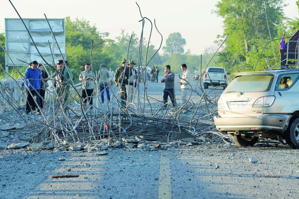 People look at a damaged bridge after Thailand carried out air strikes, between Cambodia's Oddar Meanchey and Siem Reap provinces. — AFP