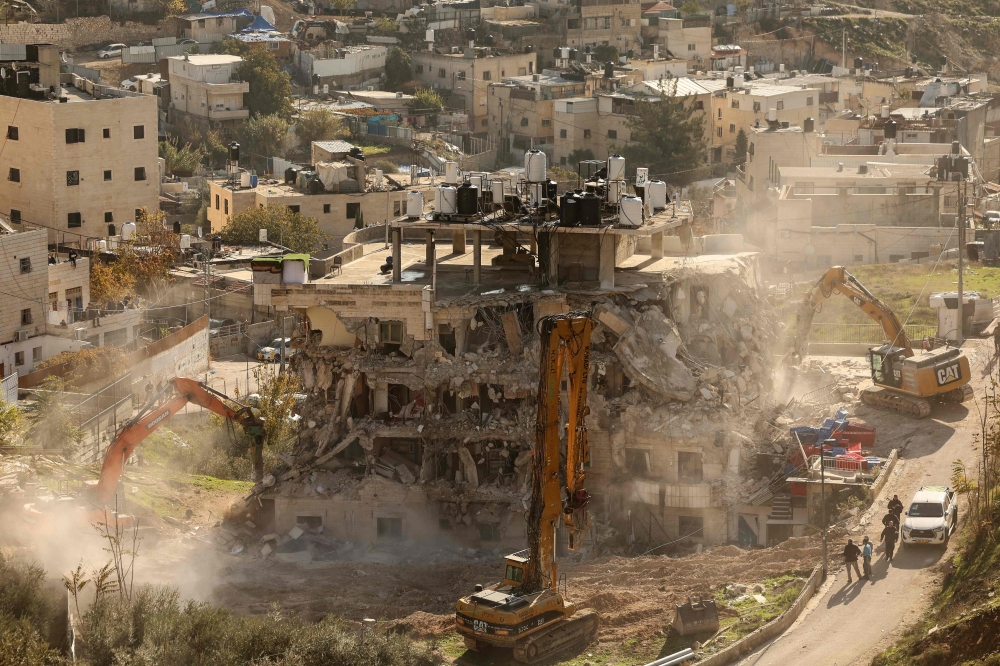 Excavators demolish a building constructed without a permit in the Wadi Qaddum area. — AFP