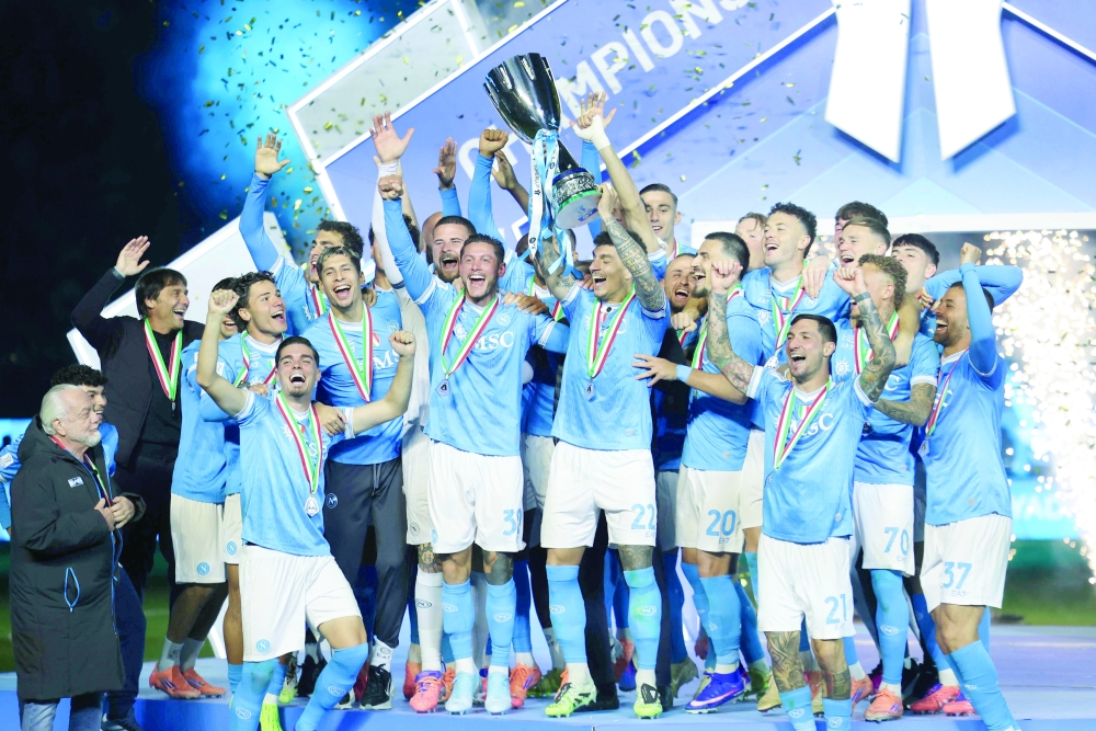 Napoli's Italian defender #22 Giovanni Di Lorenzo lifts the trophy on the podium after the Italian Super Cup final match. — AFP