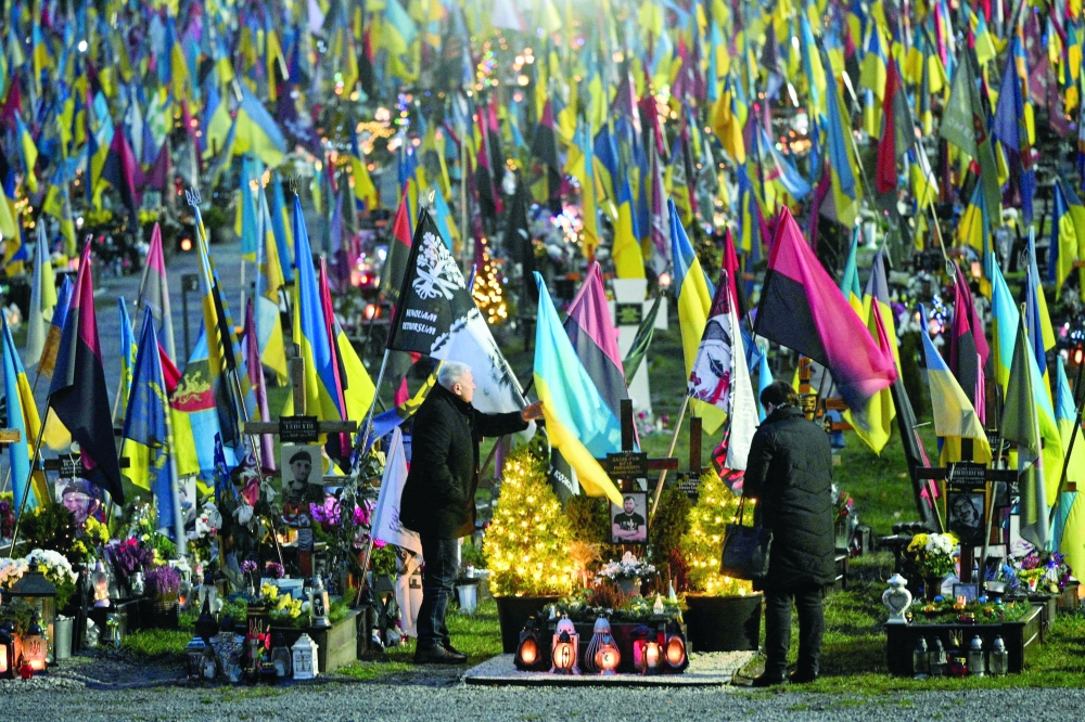 People visit the graves of fallen Ukrainian soldiers, in Lviv. — AFP