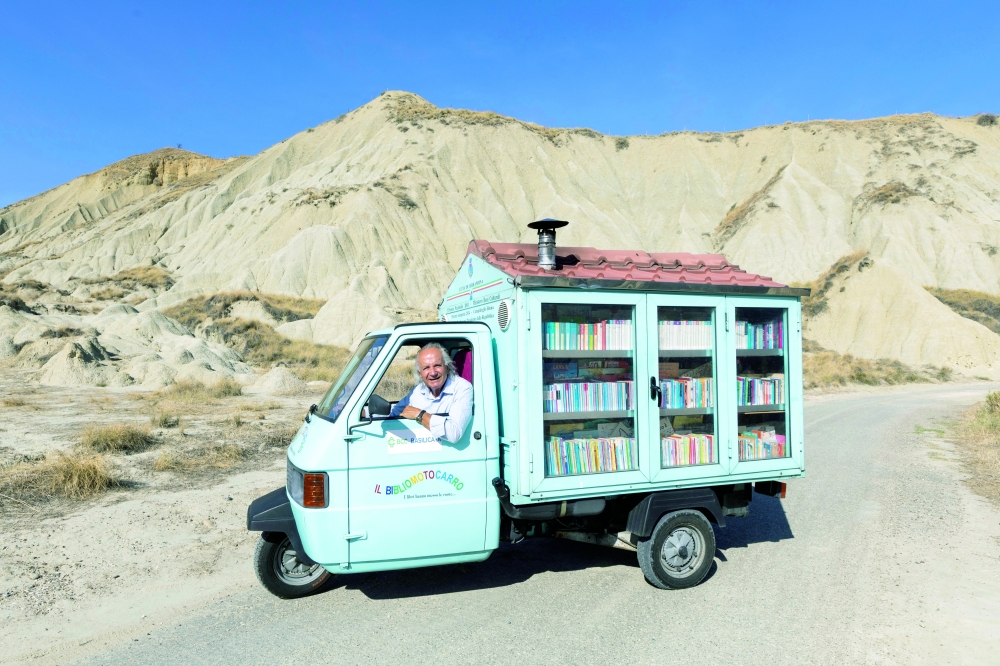 Antonio La Cava, a retired schoolteacher known as 'Maestro', drives his book-filled three-wheeler from Moliterno to Ferrandina