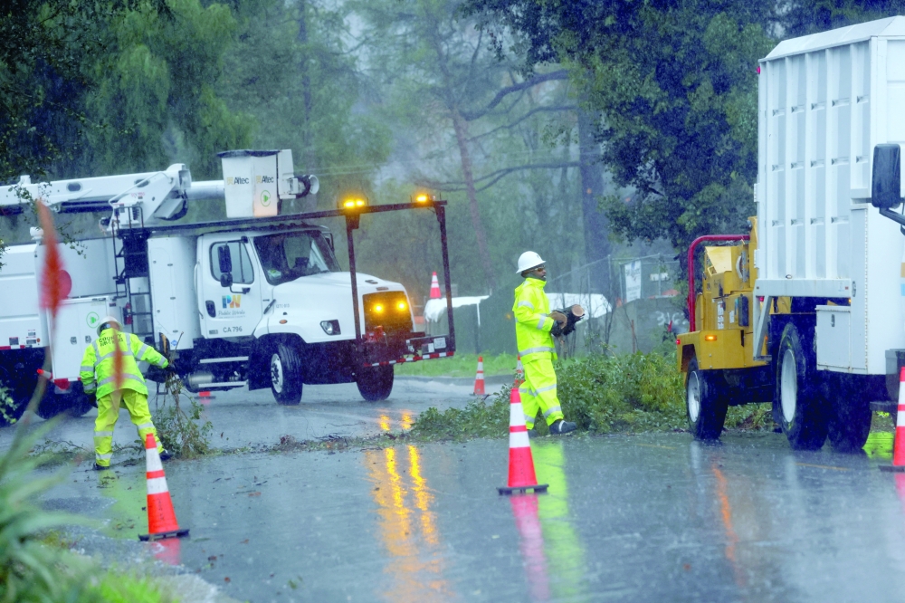 LA County Public Works staff remove a fallen tree, as heavy rains fall due to an atmospheric river, in Altadena, California, US. — Reuters