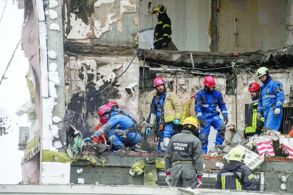 Ukrainian rescuers recover a victim's body from the rubble of a damaged residential building following Russian drones and missiles attack in Kyiv on Saturday. — AFP