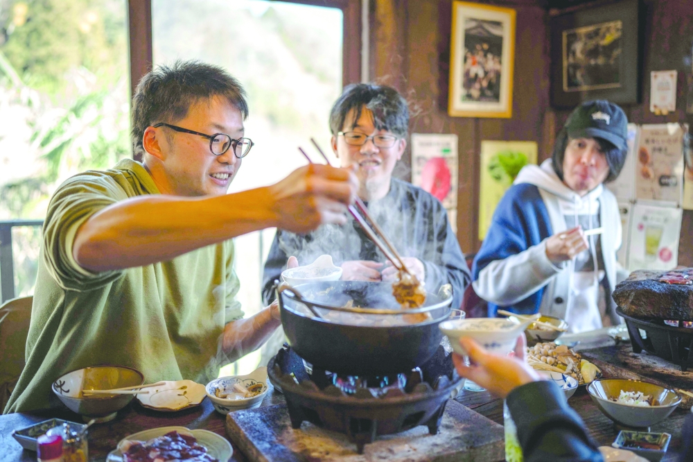 This picture taken on December 12, 2025 shows people eating bear meat hot pot at a restaurant in Chichibu, Saitama prefecture. Since Japan recorded a spike in deadly bear attacks, Koji Suzuki has struggled to keep up with booming demand for grilled cuts of the animal at his restaurant. Cooked on a stone slate -- or in hot pot with vegetables -- the meat comes from bears culled to curb maulings that have killed a record 13 people this year. - To go with 'JAPAN-ENVIRONMENT-BEAR-FOOD' by Kyoko Hasegawa and Hiroshi Hiyama in Sapporo
 (Photo by Yuichi YAMAZAKI / AFP) / To go with 'JAPAN-ENVIRONMENT-BEAR-FOOD' by Kyoko Hasegawa and Hiroshi Hiyama in Sapporo
