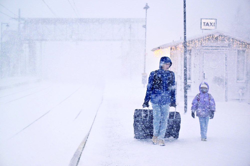 A woman and child make their way with their luggage at the train station, northern Sweden. — AFP