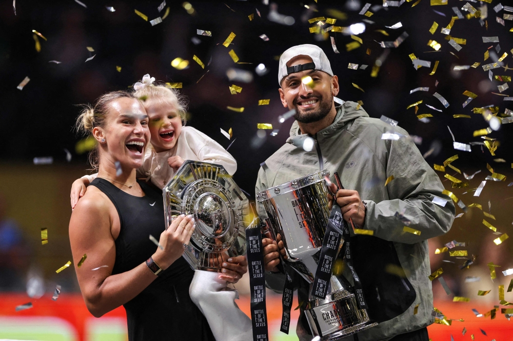 Sabalenka (L), her goddaughter Nicole, and Kyrgios celebrate with trophies 