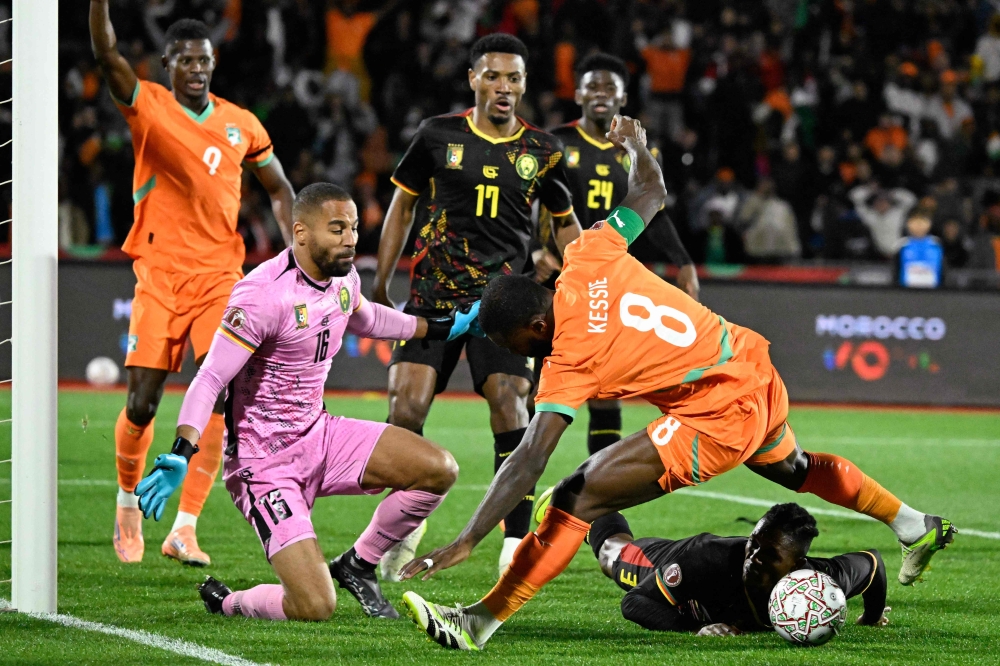 Ivory Coast's Franck (C) fights for the ball with Cameroon's Malone (R) and Cameroon's goalkeeper Epassy (L) 