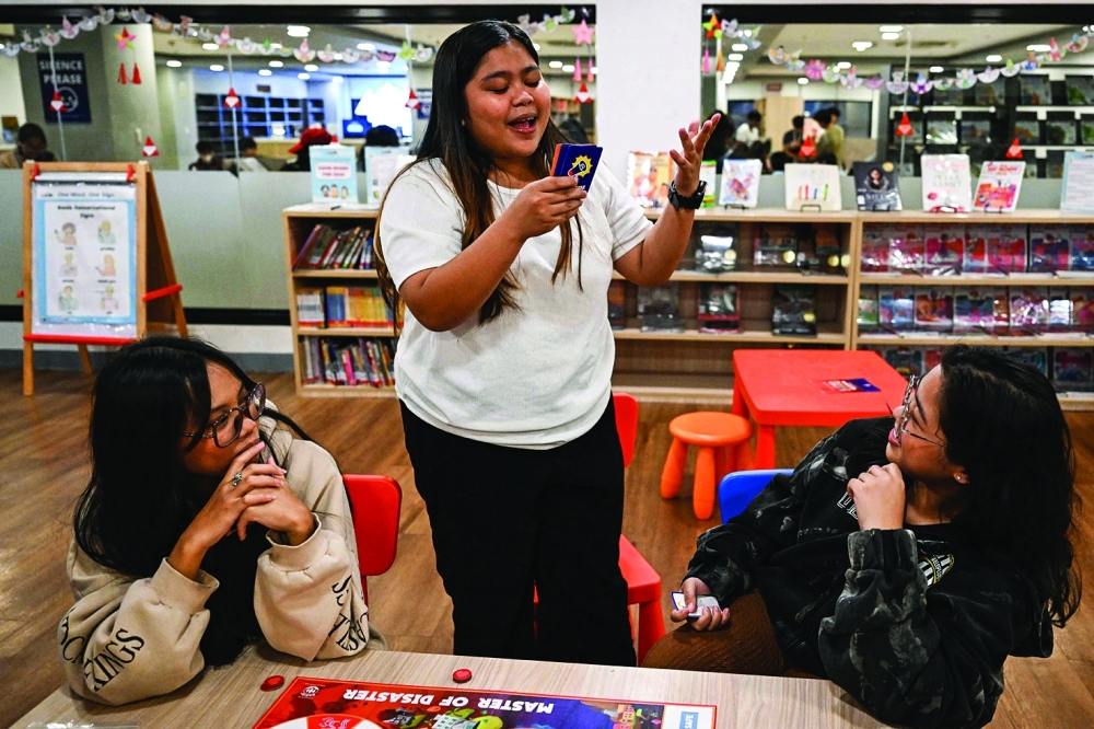 Participants playing Master of Disaster, a board game about disaster preparedness, at a library in Valenzuela, Metro Manila. — AFP