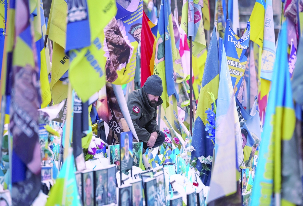 A man visits a makeshift memorial with the names of fallen service members, in Kyiv. — Reuters