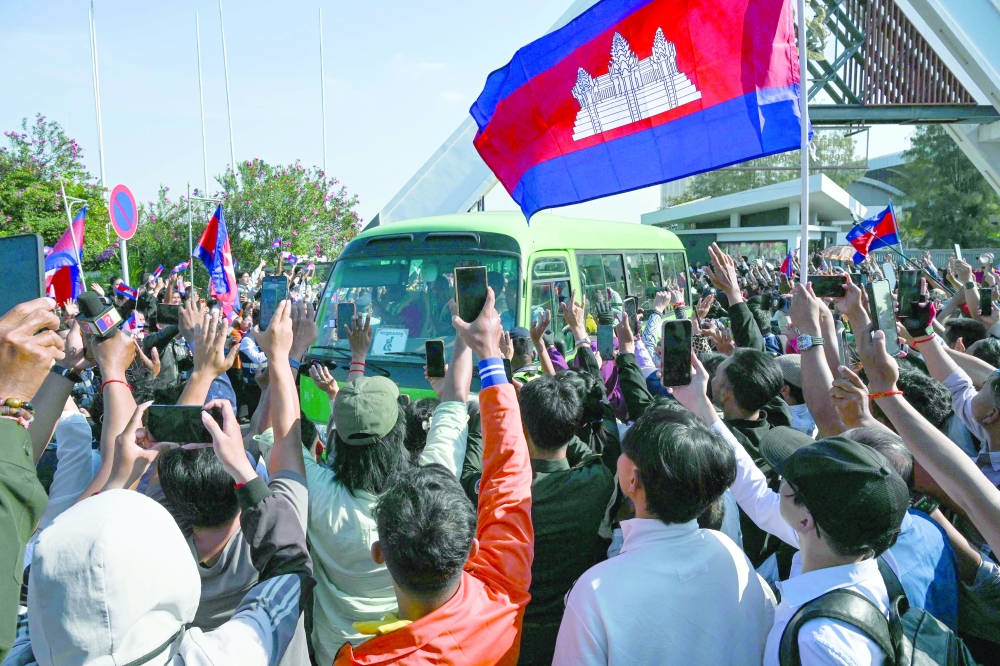 Cambodian people welcome soldiers as a bus passes by in Phnom Penh. _ AFP