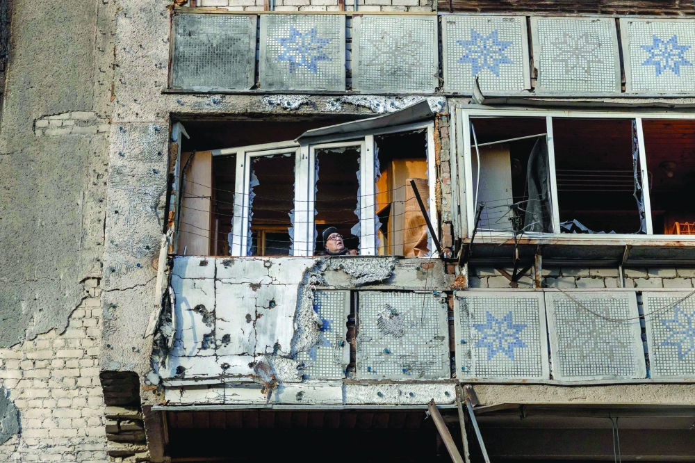 A woman stands on the balcony of a damaged residential building following an attack, in Odesa. _ AFP
