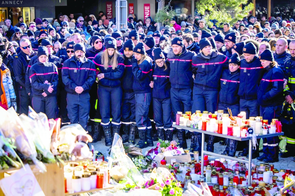Firefighters from the Municipality of Crans-Montana react as they gather around a makeshift memorial. — AFP
