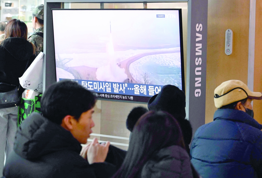 People sit as news broadcast with footage of a North Korean missile test, in Seoul. — AFP