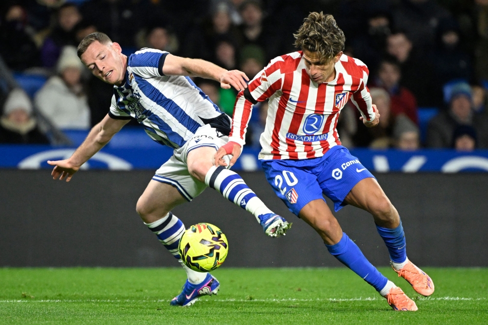 Atletico Madrid's Giuliano Simeone (R) and Real Sociedad's Sergio Gomez fight for the ball 