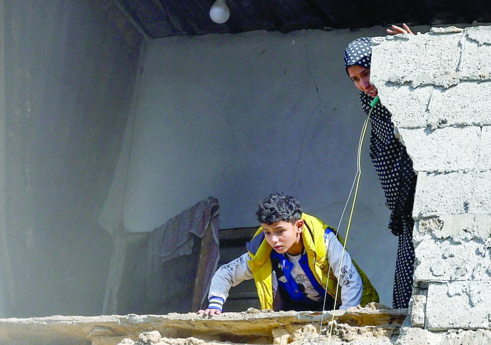 Palestinians at the site of a collapsed house that was damaged during the war by an Israeli strike.