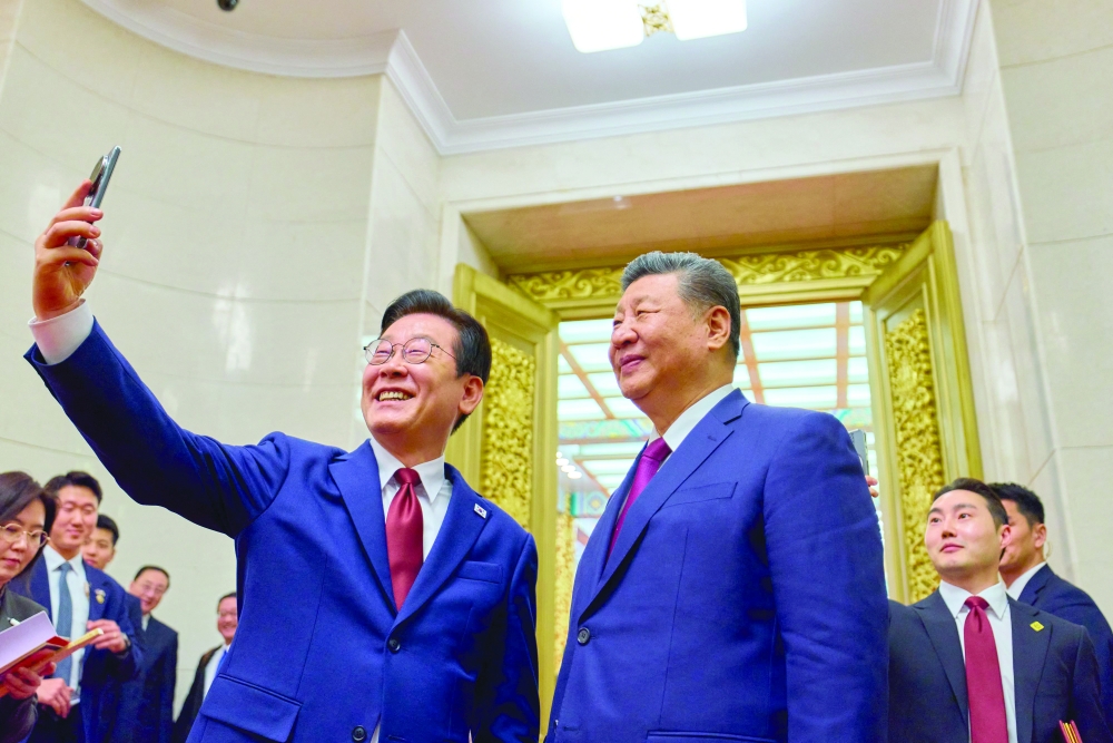 South Korea's President Lee Jae Myung (L) takes a selfie with China's President Xi Jinping (R), in Beijing. — AFP